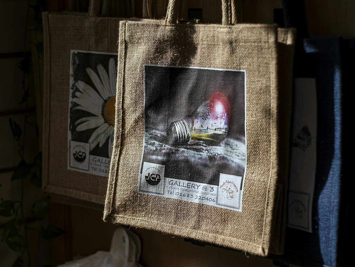 Jute bags with printed designs hanging in sunlight
