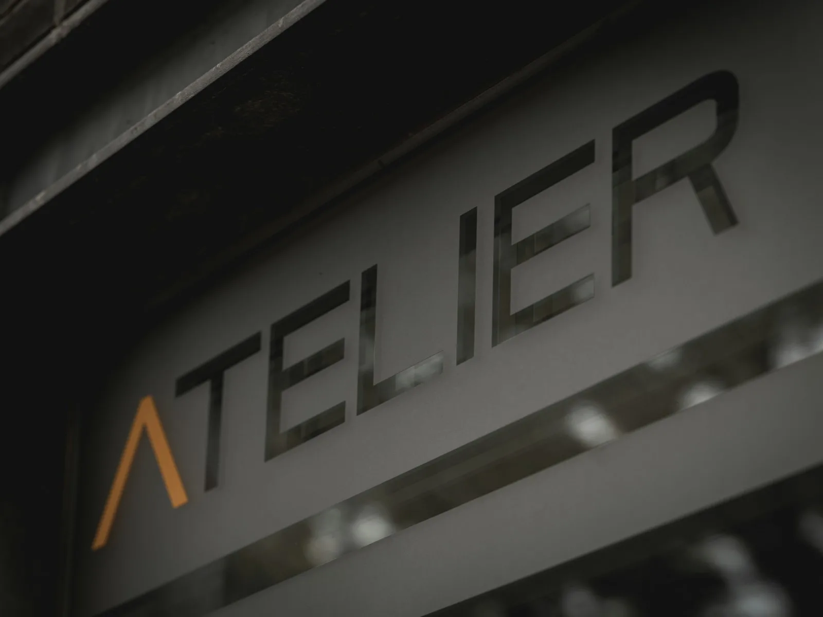 Atelier sign with stylized orange 'a' on a dark surface